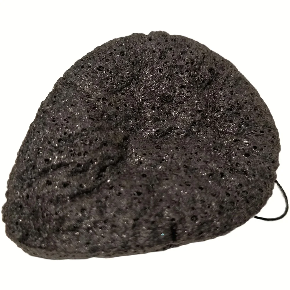 Loofys konjac gezichtsscrub, een zwarte sponsachtige spons met poreus oppervlak op een witte achtergrond