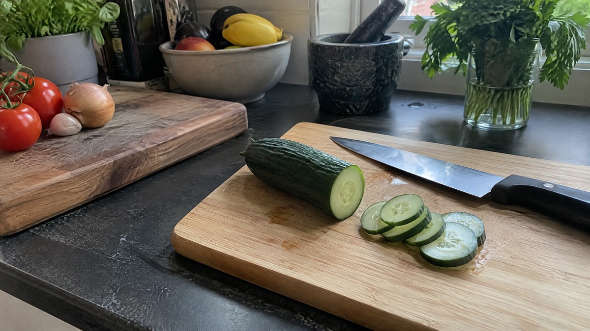 A candid phone photo in a lived-in home kitchen shows a bamboo cutting board beside a solid wooden board, with a kitchen
